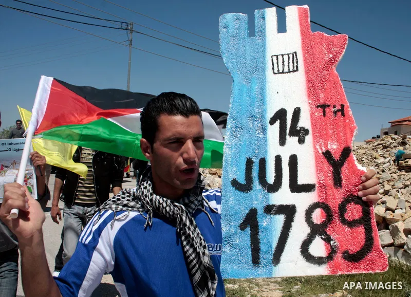 A protester holds a placard depicting the Italian flag and the birth date of Vittorio Arrigoni after kidnapping him in Gaza during a demonstration against Israel's controversial separation barrier in the West Bank villag...