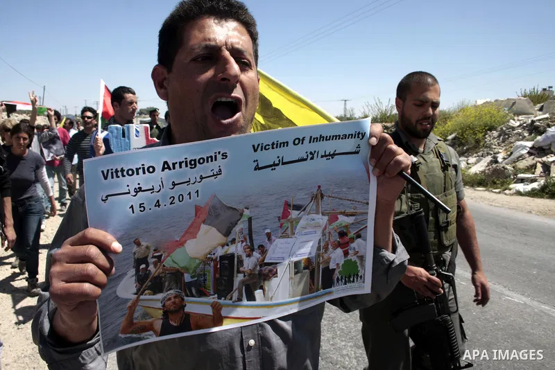 A protester holds a picture of the Italian flag and the birth date of Vittorio Arrigoni after kidnapping him in Gaza during a demonstration against Israel's controversial separation barrier in the West Bank village of Ma...