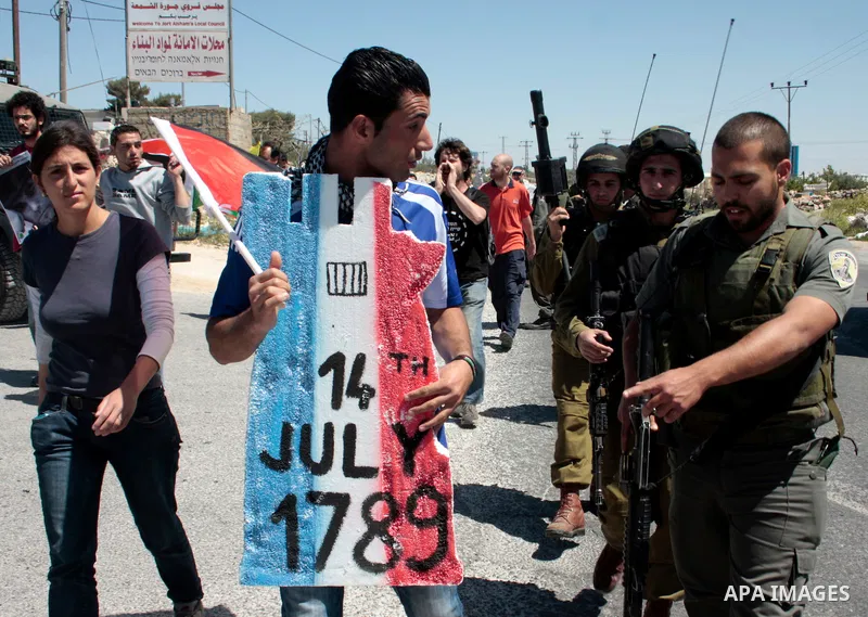 A protester holding a placard depicting the Italian flag and the birth date of Vittorio Arrigoni after kidnapping him in Gaza argue with Israeli soldiers during a demonstration against Israel's controversial separation b...