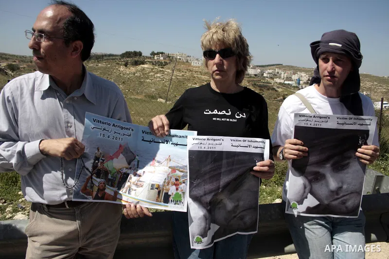 Protesters hold pictures of the Italian flag and the birth date of Vittorio Arrigoni after kidnapping him in Gaza during a demonstration against Israel's controversial separation barrier in the West Bank village of Maasa...