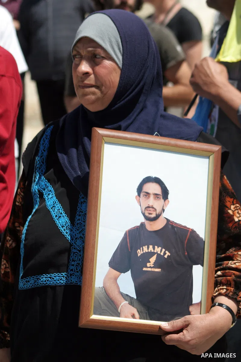 Palestinian woman holds a picture of jailed relative during a demonstration against Israel's controversial separation barrier and in support with Vittorio Arrigoni after kidnapping him in Gaza, in the West Bank village o...