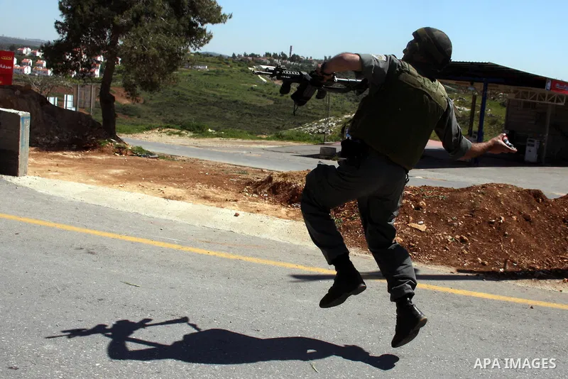 An Israeli soldier hurls tear gas canister toward Palestinian and foreign demonstrators to disperse a protest against the expropriation of land to expand the Jewish settlement of Halmish, in the Palestinian village of Na...