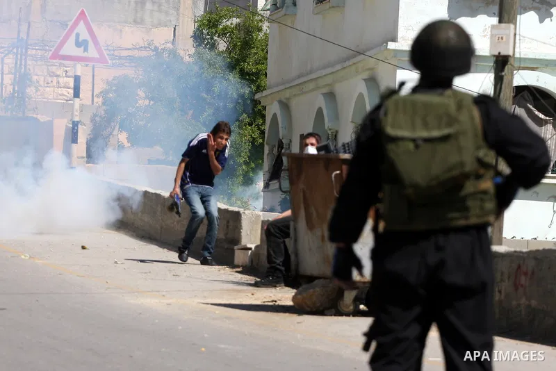 Palestinian and foreign demonstrators run away from tear gas fired by Israeli soldiers to disperse a protest against the expropriation of land to expand the Jewish settlement of Halmish, in the Palestinian village of Nab...