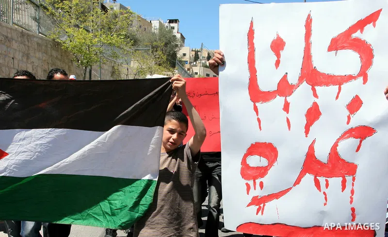 Palestinians hold national flag and placards during a protest in support with Gaza Strip and against the Israeli aggression on it, in the east Jerusalem neighborhood of Silwan on April 15, 2011. Photo by Sliman Khader