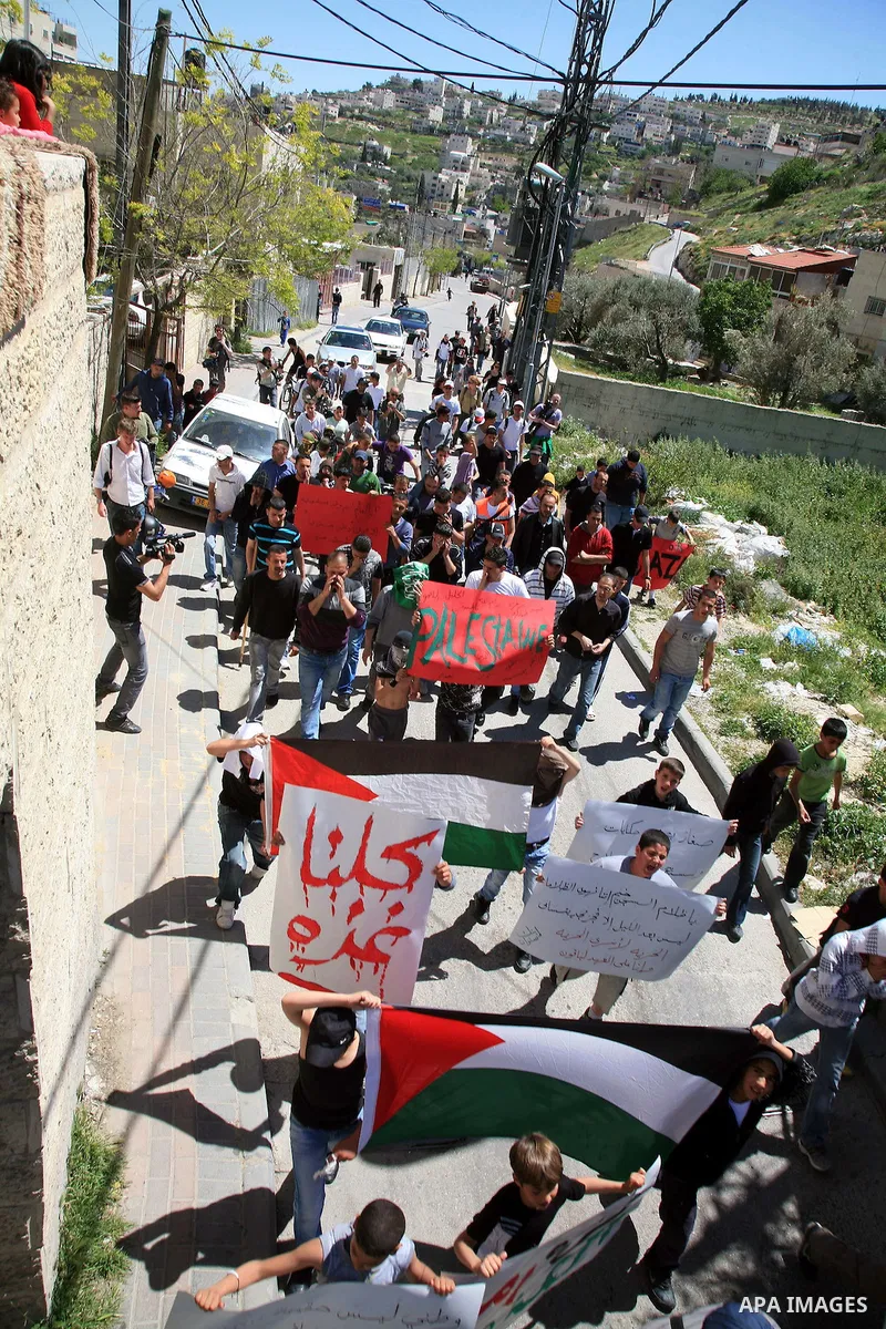 Palestinians hold national flag and placards during a protest in support with Gaza Strip and against the Israeli aggression on it, in the east Jerusalem neighborhood of Silwan on April 15, 2011. Photo by Sliman Khader