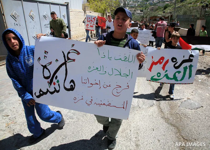 Palestinians hold national flag and placards during a protest in support with Gaza Strip and against the Israeli aggression on it, in the east Jerusalem neighborhood of Silwan on April 15, 2011. Photo by Sliman Khader