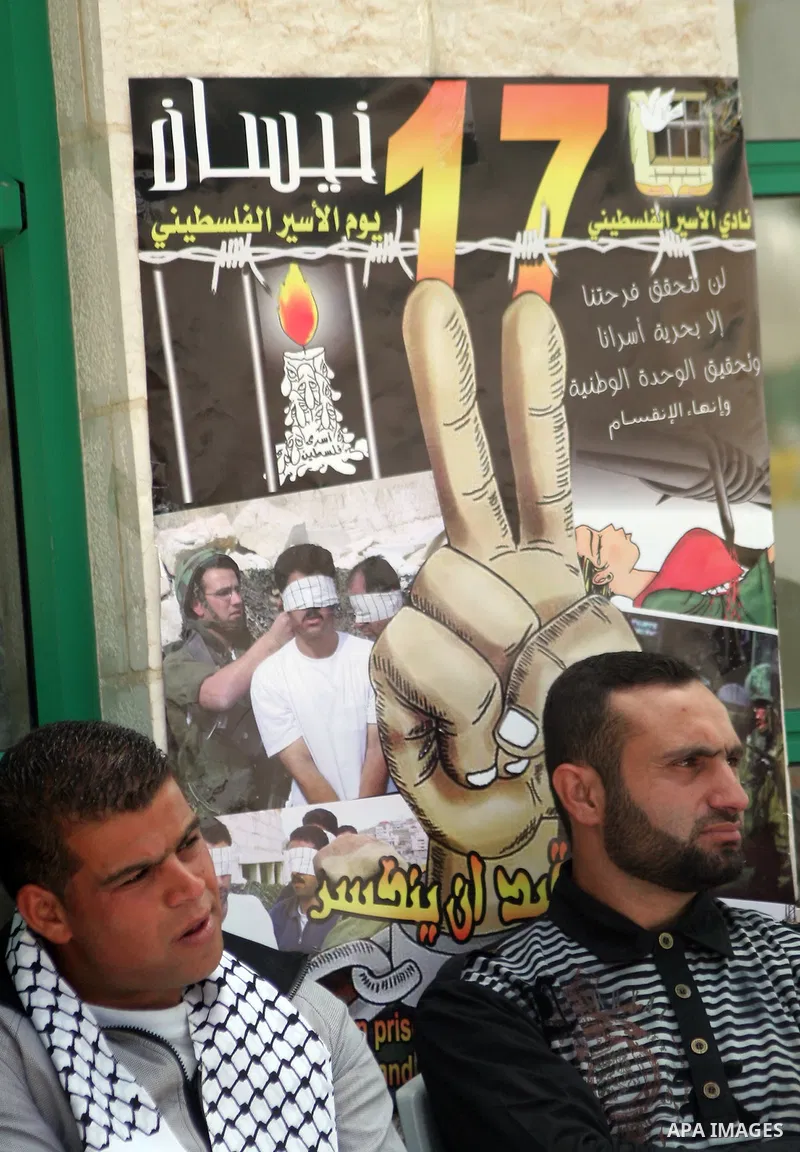 Palestinian students for the al-Quds Open University sits next a poster as Palestinians across the Israeli occupied West Bank and Gaza Strip mark "Prisoner Day", calling for Palestinians being held in Israeli jails to be...