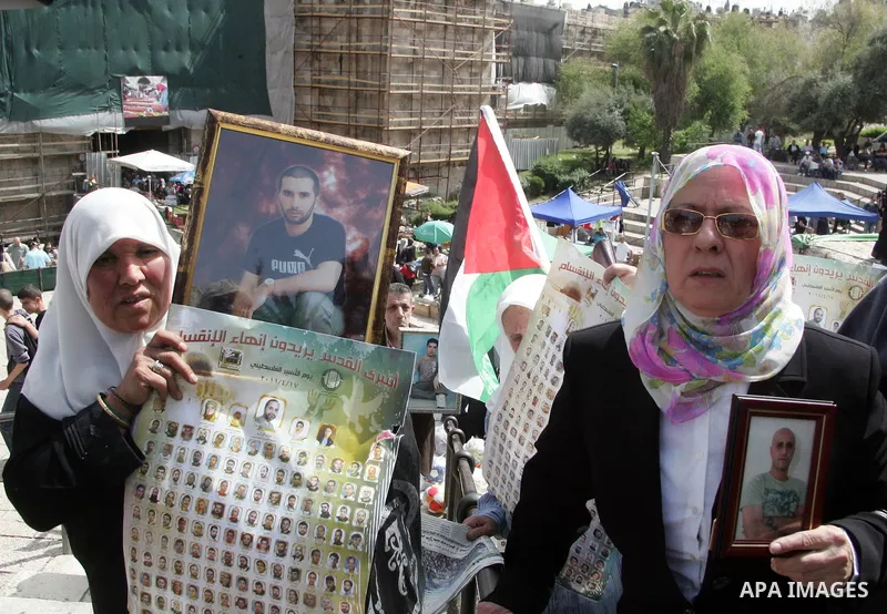 Palestinians hold pictures of prisoners jailed in Israel, including Fatah leader Marwan Barghouti, foreground left and right, during a protest for the upcoming Prisoner's Day, in the West Bank city of Jerusalem Saturday,...