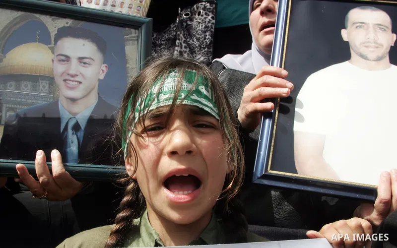 Palestinians hold pictures of prisoners jailed in Israel, including Fatah leader Marwan Barghouti, foreground left and right, during a protest for the upcoming Prisoner's Day, in the West Bank city of Jerusalem Saturday,...