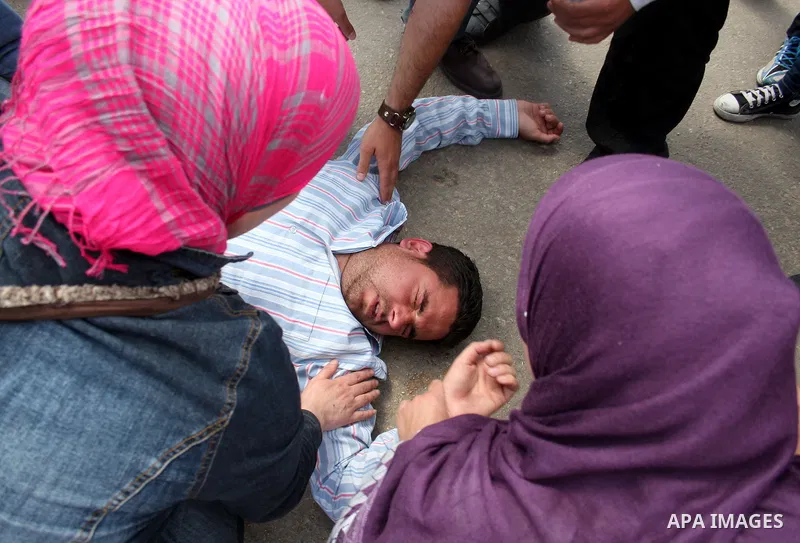 Palestinians and foreigners gather around a Palestinian youth after he collapsed by tear gas fired by Israeli soldiers during a protest outside Ofer prison, near the West Bank city of Ramallah, April 17, 2011, calling fo...