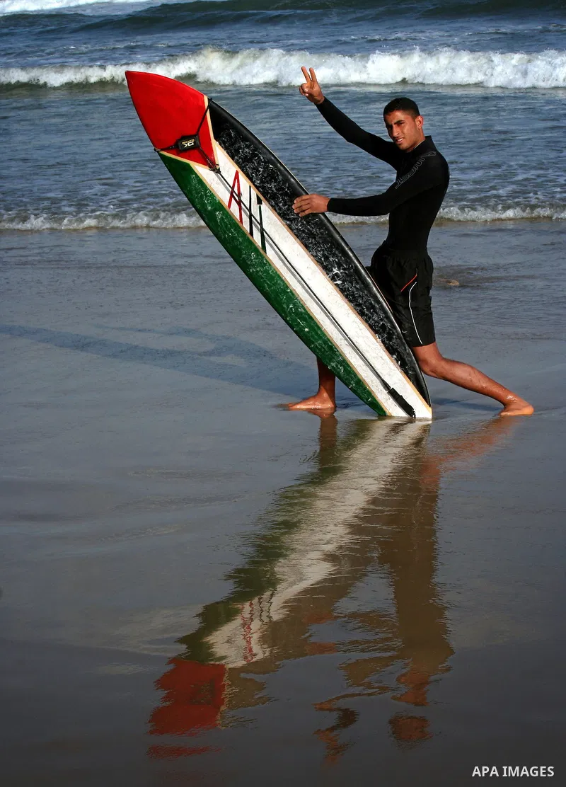 In this photo taken on April 14,2011, a Palestinian youth surf in the Mediterranean Sea off the coast of Gaza City, as a hot weather hits Gaza Strip. Photo by Mahmoud Nassar