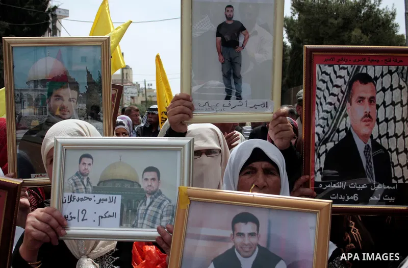 Palestinians hold up a photo of jailed family members as they take part in a rally, one of several taking place across the Israeli occupied West Bank and Gaza Strip, calling for the release of Palestinians being held in...