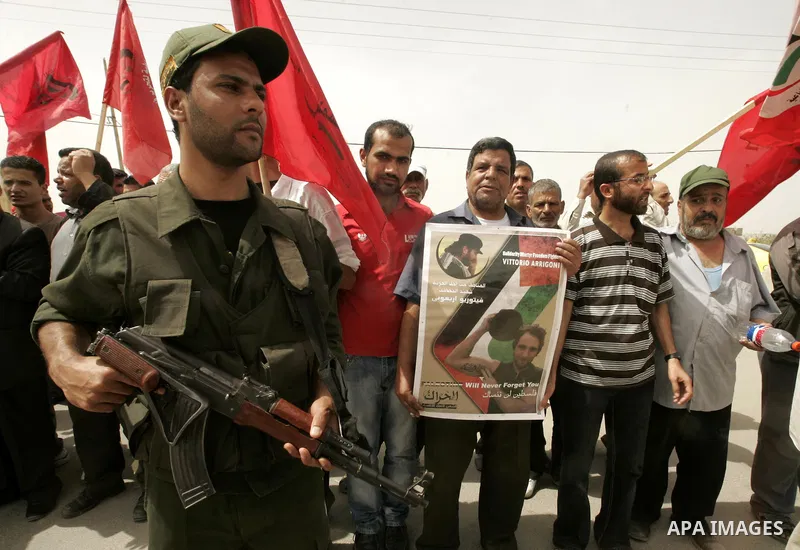 Hamas security forces stand guard as Palestinians and foreigners mourn during the "state funeral" of Italian activist Vittorio Arrigoni in Rafah, southern Gaza Strip, on April 18, 2011 before the transferring of his body...
