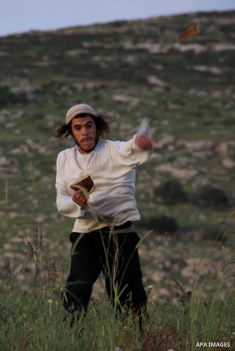 A Jewish settler from the Har Bracha settlement holds stones as he readies to lob them at local Palestinian villagers during clashes close to the Palestinian village of Burin in the Israeli occupied West bank on April 19...