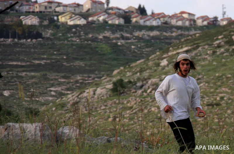 A Jewish settler from the Har Bracha settlement holds stones as he readies to lob them at local Palestinian villagers during clashes close to the Palestinian village of Burin in the Israeli occupied West bank on April 19...