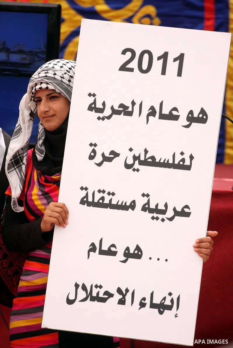 A Palestinian girl holds up slogans during the opening ceremony of the 6th Bilin international conference for Palestinian Popular Resistance on April 20, 2011 in West Bank village of Bilin, near Ramallah. Fayyad called o...