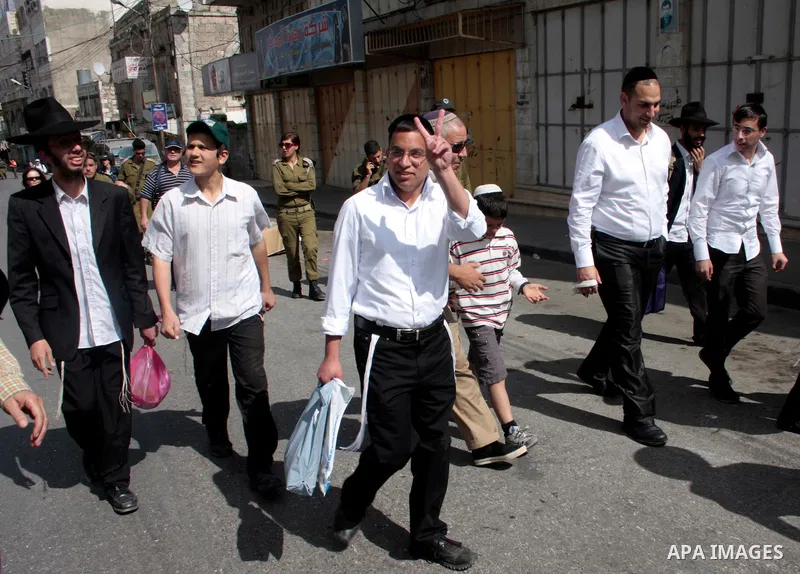 Israeli settlers walk in an empty street in Hebron in the occupied West Bank on April 20, 2011.The Israeli army imposed a temporary curfew on Palestinians in the city centre to allow Jewish settlers to visit the tomb of...