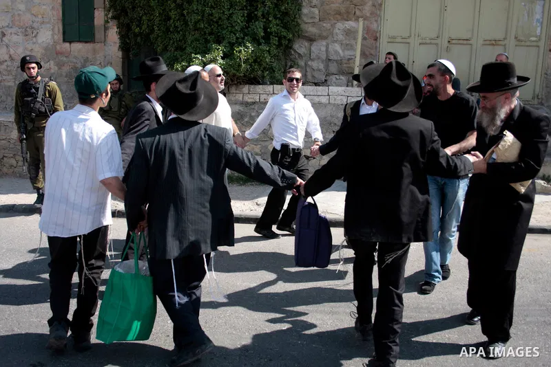 Israeli settlers walk in an empty street in Hebron in the occupied West Bank on April 20, 2011.The Israeli army imposed a temporary curfew on Palestinians in the city centre to allow Jewish settlers to visit the tomb of...