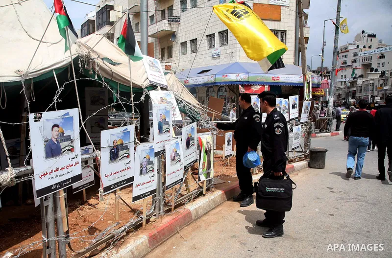 Palestinian policeman looks at the pictures of Palestinian prisoners in front of a tent in Manara Square in Ramallah, West Bank, April 21, 2011. Photo by Sliman Khader