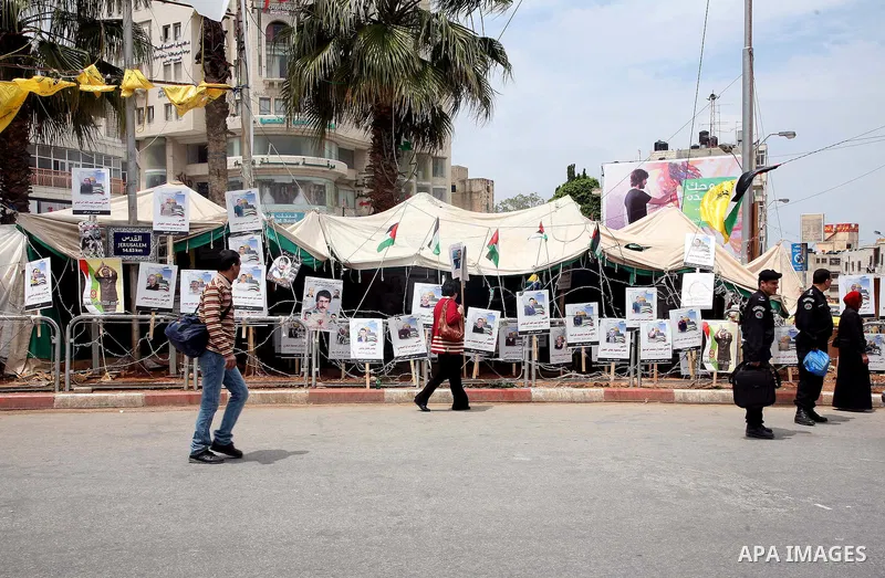 Palestinian policeman looks at the pictures of Palestinian prisoners in front of a tent in Manara Square in Ramallah, West Bank, April 21, 2011. Photo by Sliman Khader