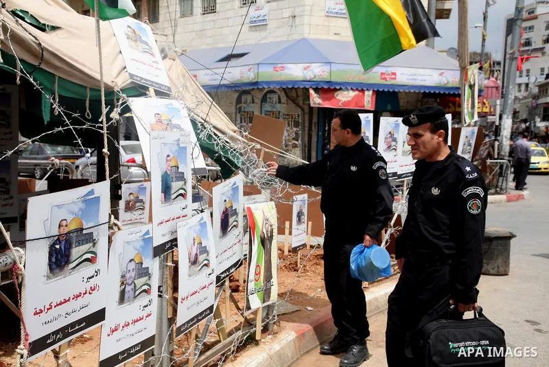 Palestinian policeman looks at the pictures of Palestinian prisoners in front of a tent in Manara Square in Ramallah, West Bank, April 21, 2011. Photo by Sliman Khader