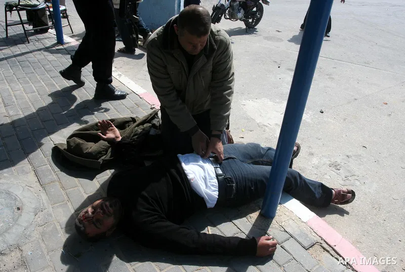Palestinians gather around an injured man after a tank fired shots toward him in the eastern Gaza city on April 22,2011. Three Palestinians were lightly to moderately wounded when a tank fired at a group of people near t...