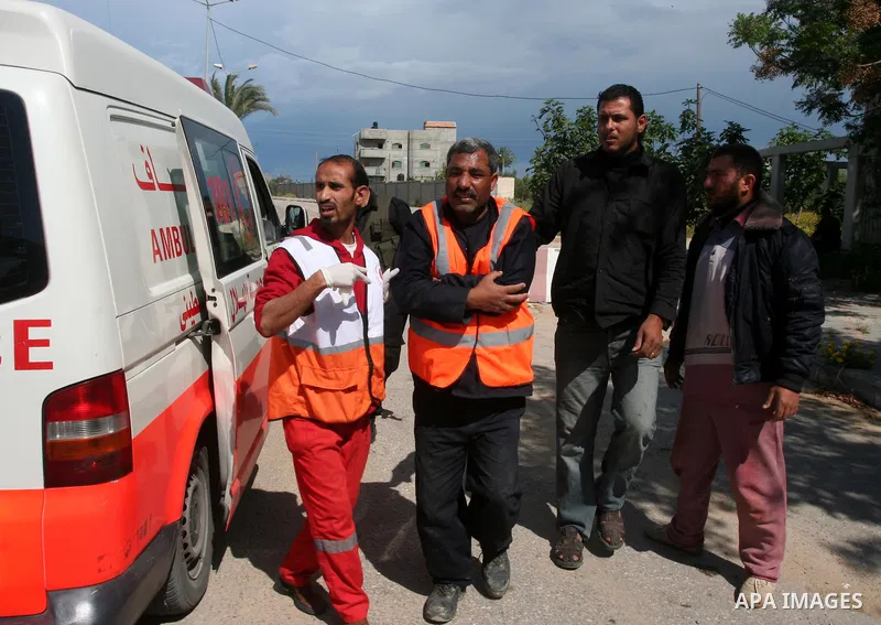 Palestinians help an injured worker after a tank fired shots toward him in the eastern Gaza city on April 22,2011. Three Palestinians were lightly to moderately wounded when a tank fired at a group of people near the Kar...