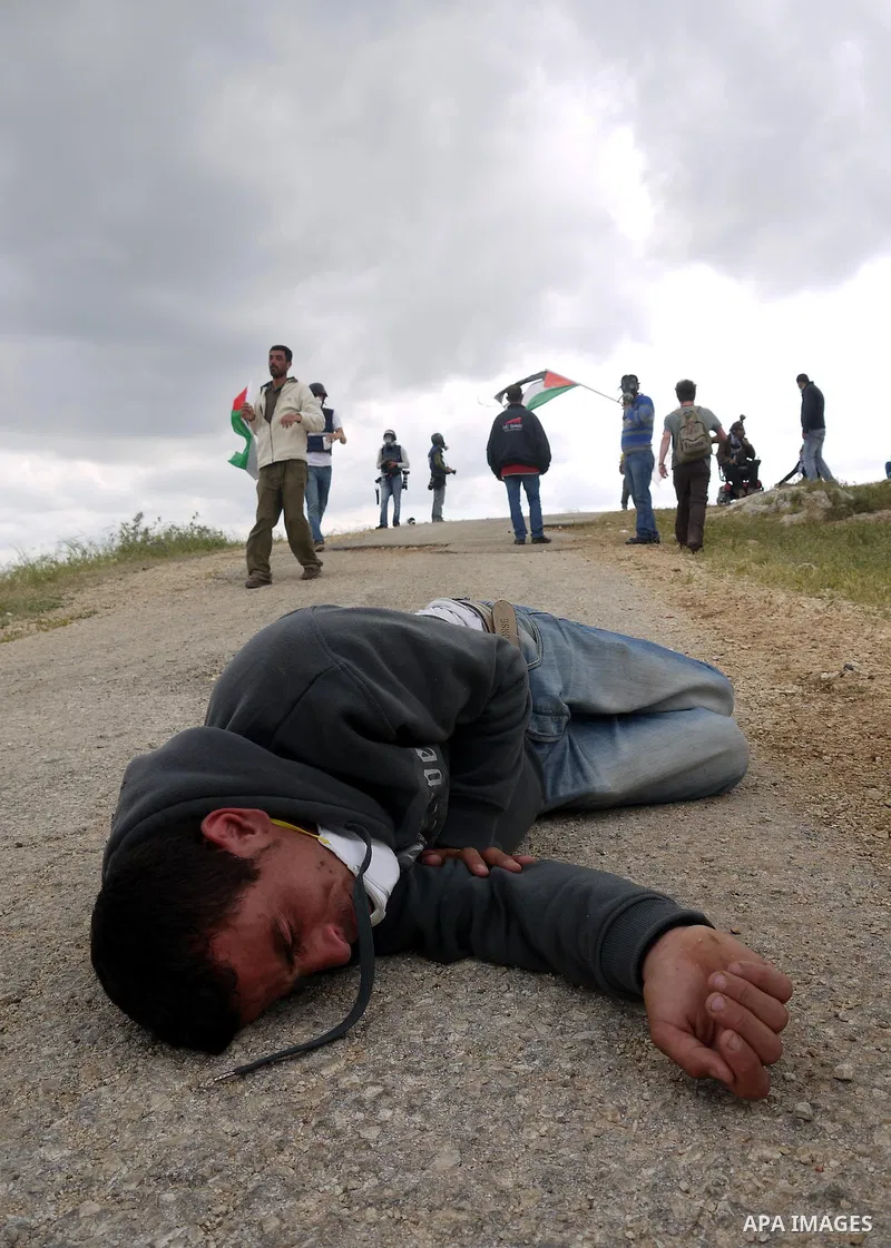 A Palestinian protester collapses from tear gas canisters fired by Israeli soldiers during the weekly demonstration against Israel's controversial separation barrier in the village of Bilin, near the West Bank city of Ra...