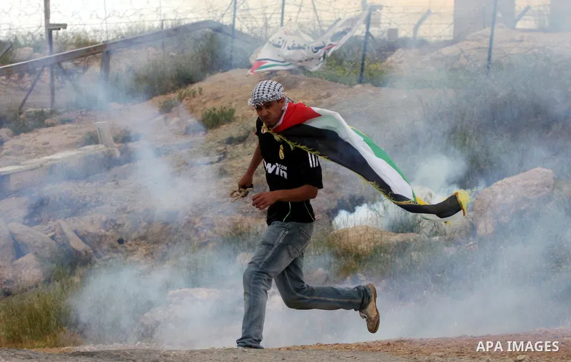 A Palestinian protester runs for cover from tear gas canisters fired by Israeli soldiers during the weekly demonstration against Israel's controversial separation barrier in the village of Bilin, near the West Bank city...