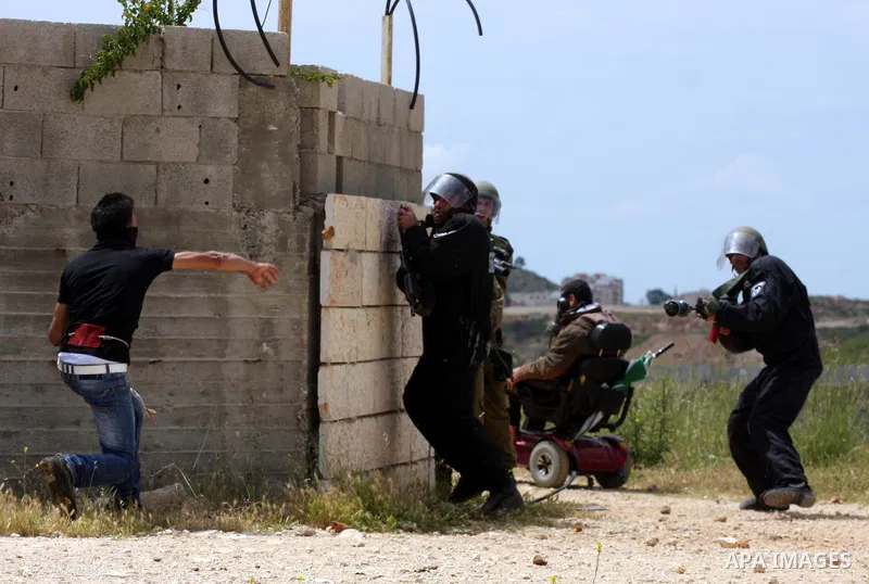 A Palestinian protester hurls stones toward Israeli soldiers during the weekly demonstration against Israel's controversial separation barrier in the village of Bilin, near the West Bank city of Ramallah on April 22, 201...