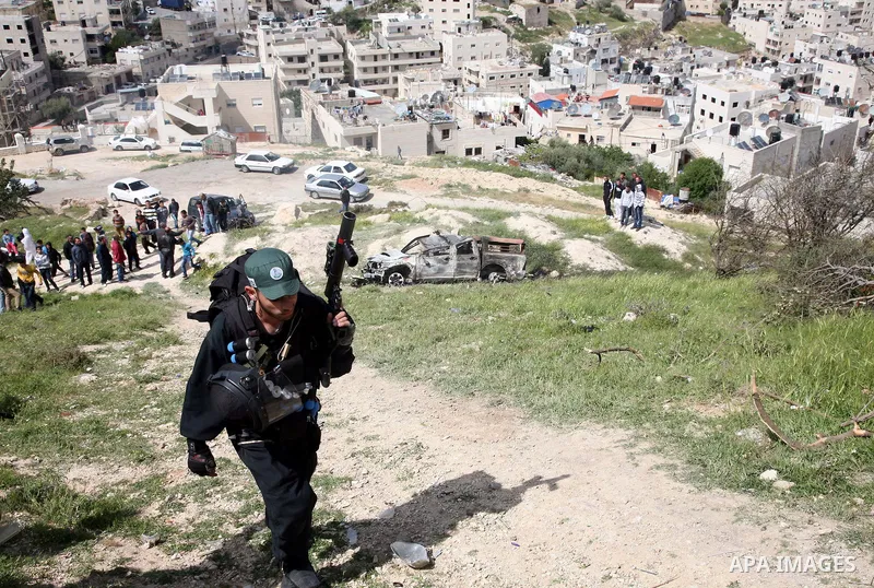 Israeli soldiers stand guard near a burnt Israeli army vehicle on April 22, 2011 after it flipped over and was set alight by Palestinian youths in the flashpoint neighbourhood of Issawiya in annexed east Jerusalem. No in...