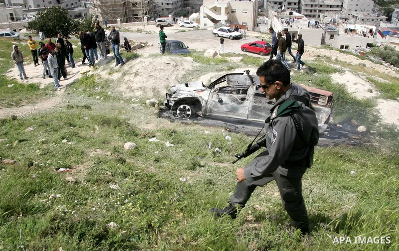 Israeli soldiers stand guard near a burnt Israeli army vehicle on April 22, 2011 after it flipped over and was set alight by Palestinian youths in the flashpoint neighbourhood of Issawiya in annexed east Jerusalem. No in...