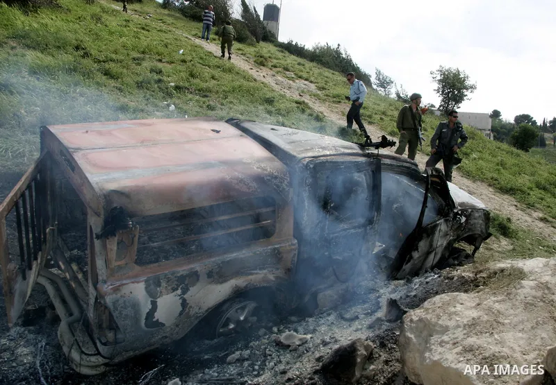 Israeli soldiers stand guard near a burnt Israeli army vehicle on April 22, 2011 after it flipped over and was set alight by Palestinian youths in the flashpoint neighbourhood of Issawiya in annexed east Jerusalem. No in...