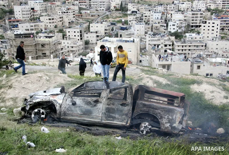Masked Palestinian youths celebrate near a burnt Israeli army vehicle on April 22, 2011 after it flipped over and was set alight by Palestinian youths in the flashpoint neighbourhood of Issawiya in annexed east Jerusalem...