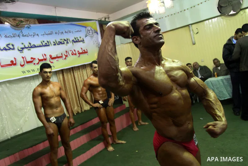 Palestinian men take part during competing in a bodybuilding contest at a hall in Gaza city, Friday, April 22, 2011. Many of the men use women's cosmetics, mud, or paint to enhance their muscles. Number of men from aroun...