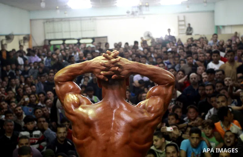Palestinian men take part during competing in a bodybuilding contest at a hall in Gaza city, Friday, April 22, 2011. Many of the men use women's cosmetics, mud, or paint to enhance their muscles. Number of men from aroun...