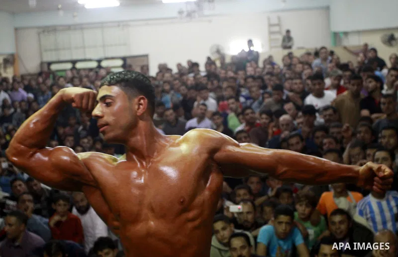 Palestinian men take part during competing in a bodybuilding contest at a hall in Gaza city, Friday, April 22, 2011. Many of the men use women's cosmetics, mud, or paint to enhance their muscles. Number of men from aroun...