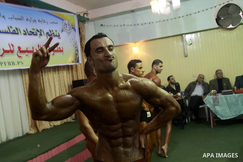 Palestinian men take part during competing in a bodybuilding contest at a hall in Gaza city, Friday, April 22, 2011. Many of the men use women's cosmetics, mud, or paint to enhance their muscles. Number of men from aroun...