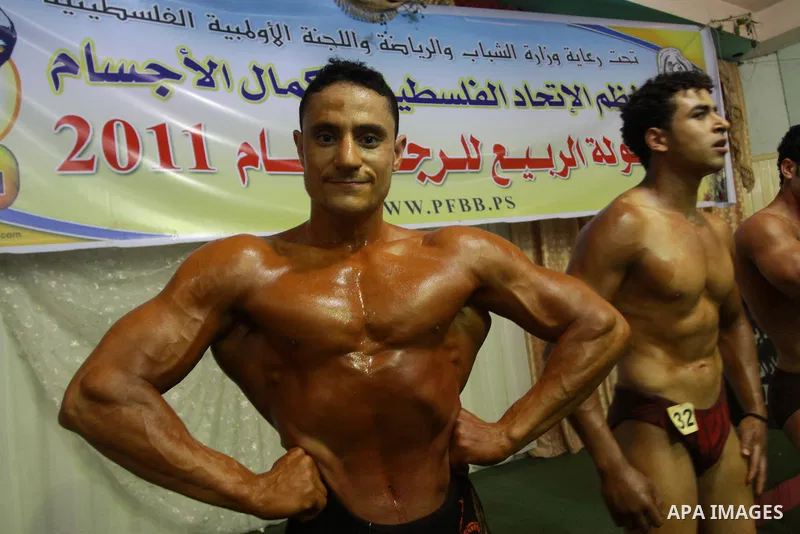 Palestinian men take part during competing in a bodybuilding contest at a hall in Gaza city, Friday, April 22, 2011. Many of the men use women's cosmetics, mud, or paint to enhance their muscles. Number of men from aroun...
