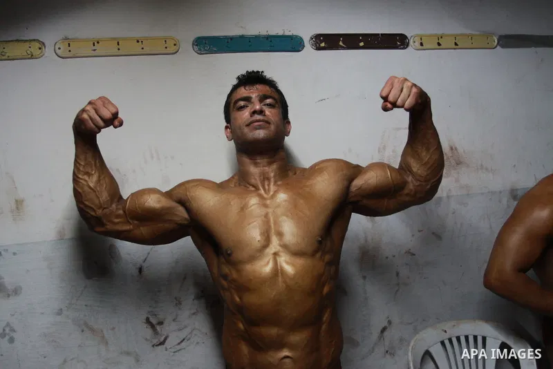Palestinian men take part during competing in a bodybuilding contest at a hall in Gaza city, Friday, April 22, 2011. Many of the men use women's cosmetics, mud, or paint to enhance their muscles. Number of men from aroun...