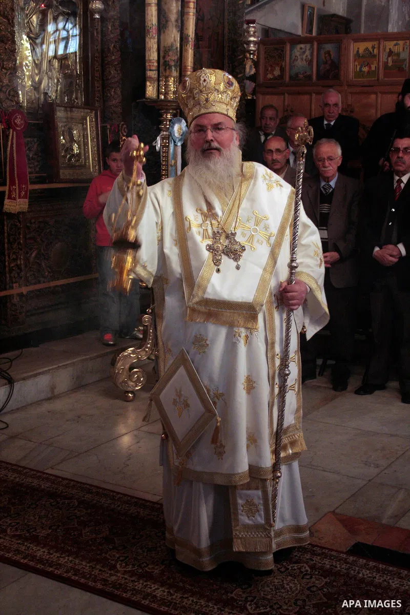 The head of the Greek Orthodox church in Bethlehem Bishop Theofilactos passes the 'Holy Fire' to worshippers brought from the Church of the Holy Sepulchre in Jerusalem during the 'Holy Fire' ceremony on the eve of the Or...