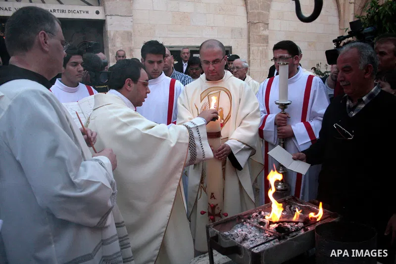 A Catholic priest lights a Paschal candle inside the Church of the Nativity compound at the opening of the Easter Vigil on Holy Saturday late April 23, 2011 in the West Bank town of Bethlehem. Christians of the western c...