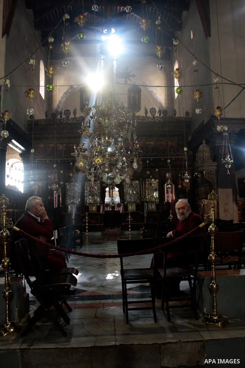Christian sits pass through a shaft of light entering the Church of the Nativity in the West Bank town of Bethlehem on April 24,2011.The light passes through an Orthodox Christian section of the church in the central nav...