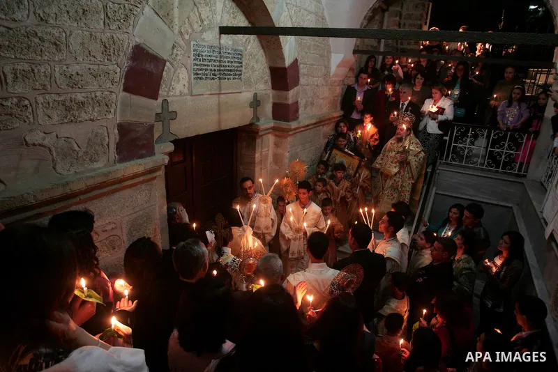 Christian Orthodox hold up candles lit from the 'Holy Fire' as thousands gather in the Church in Gaza City on April 24, 2011. Photo by Mohammed Othman