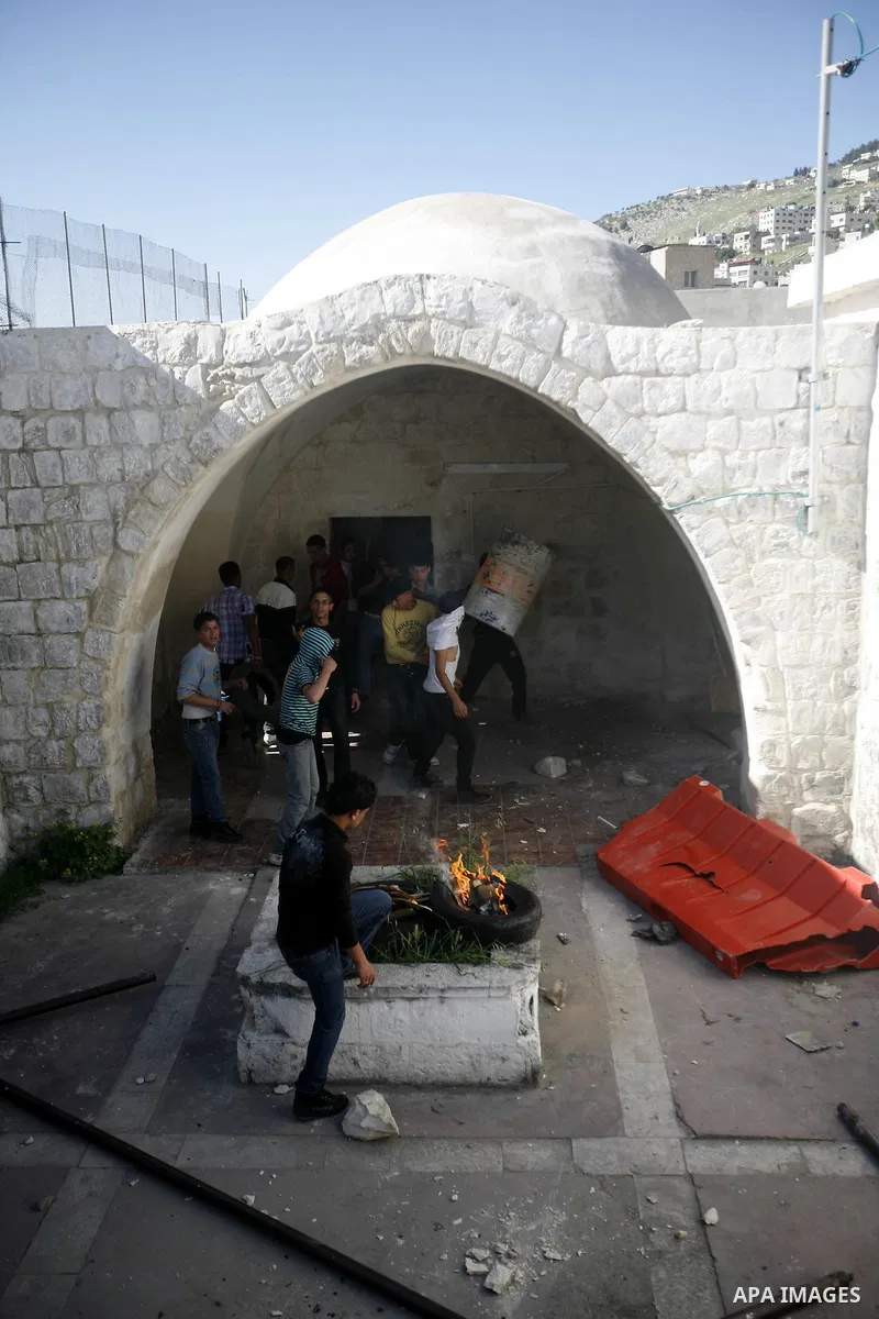 Palestinian youths take cover inside the entrance to the shrine of Joseph's Tomb in the West Bank city of Nablus on April 24, 2011 as clashes erupted after an Israeli worshipper was shot dead by Palestinian policemen nea...
