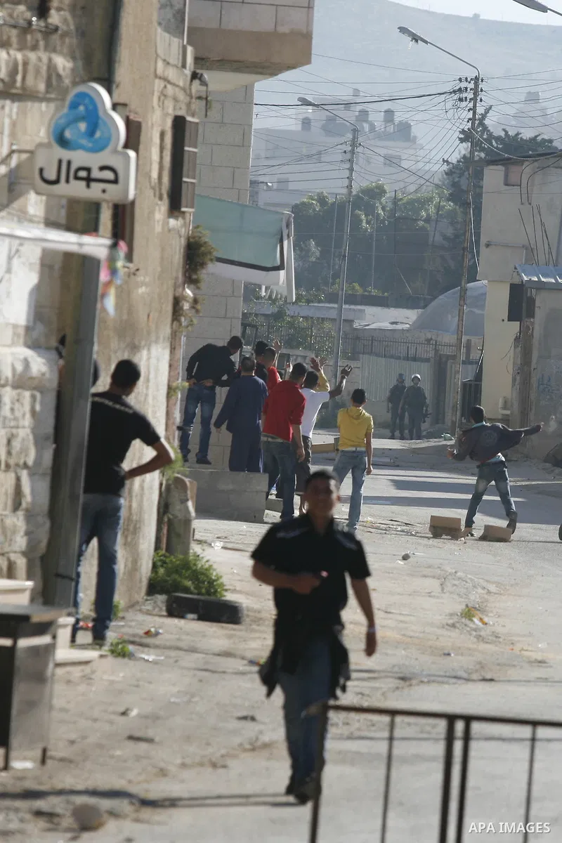 Palestinian youth throw stones towards Israeli soldiers patrolling near the shrine of Joseph's Tomb in the West Bank city of Nablus on April 24, 2011 as clashes erupted after an Israeli worshipper was shot dead by Palest...