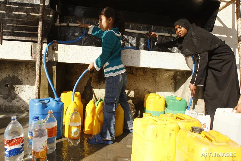 Palestinians fill bottles with water from a public tap in the United Nations Relief and Works Agency (UNRWA) headquarters in Rafah refugee camp in the southern of Gaza strip on April 26, 2011. Photo by Abed Rahim Khatib