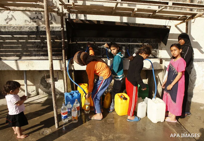 Palestinians fill bottles with water from a public tap in the United Nations Relief and Works Agency (UNRWA) headquarters in Rafah refugee camp in the southern of Gaza strip on April 26, 2011. Photo by Abed Rahim Khatib