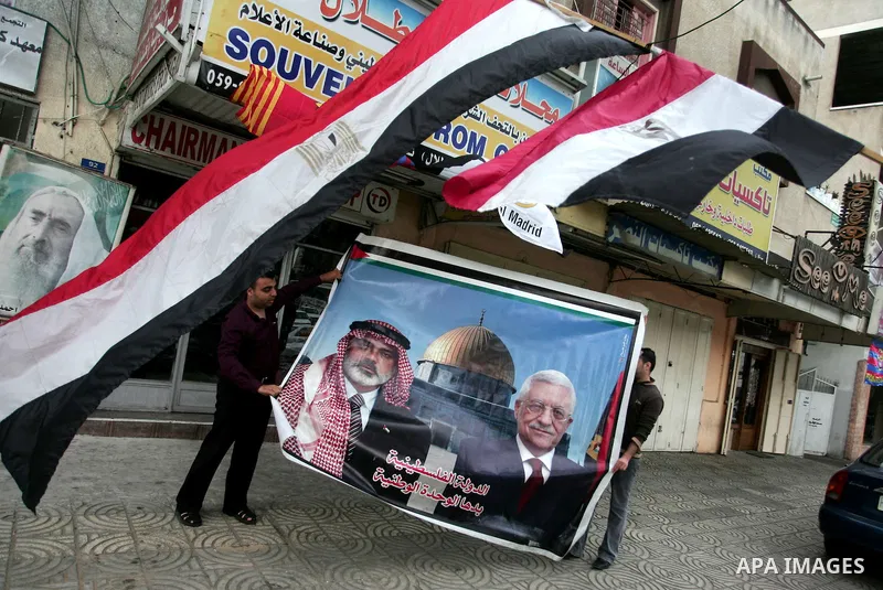 Palestinian men carry a poster for the Palestinian President Mahmoud Abbas and Palestinian Prime Minister in Gaza Strip, Ismail Hanieyah, in Gaza City on April 28, 2011 as Palestinians in the Gaza Strip and the West Bank...