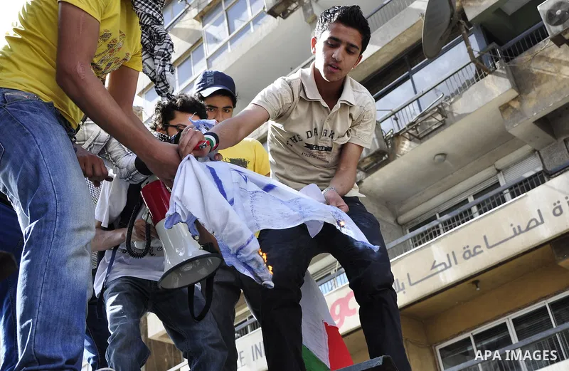 Egyptian protesters burn the Israeli flag and wave the Palestinian flag during a demonstration in front of the Israeli embassy in Cairo on April 29, 2011, calling for opening the border with the Gaza Strip and in support...
